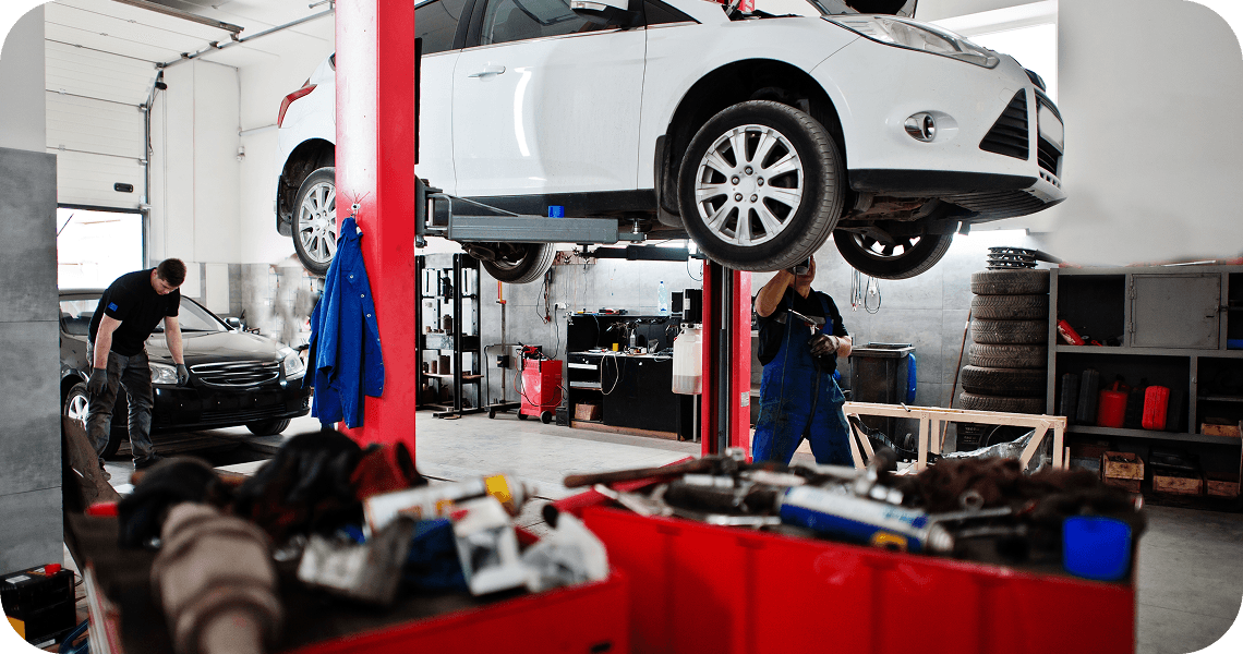 A white car raised on a lift in a workshop.