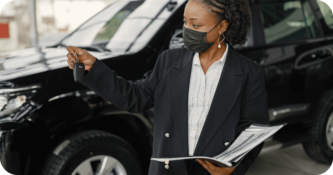A fleet officer holding documents and a car key beside a black SUV.