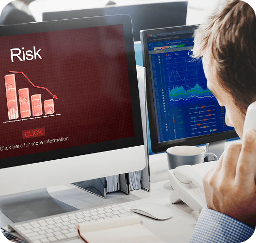An analyst reviewing a falling risk chart beside live operations data.